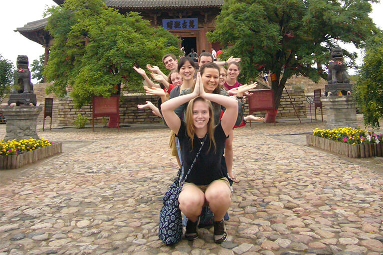 Students are posing in a straight line using different hand positions.