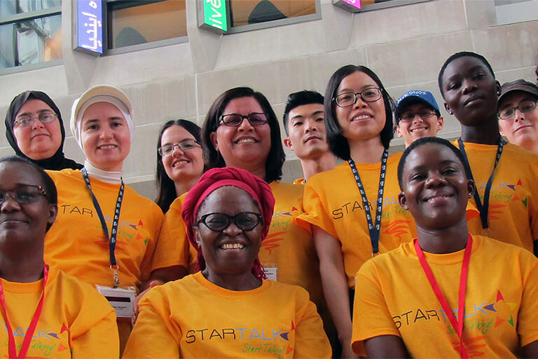 A group photo posing in the HLS atrium with everyone wearing Startalk shirts.
